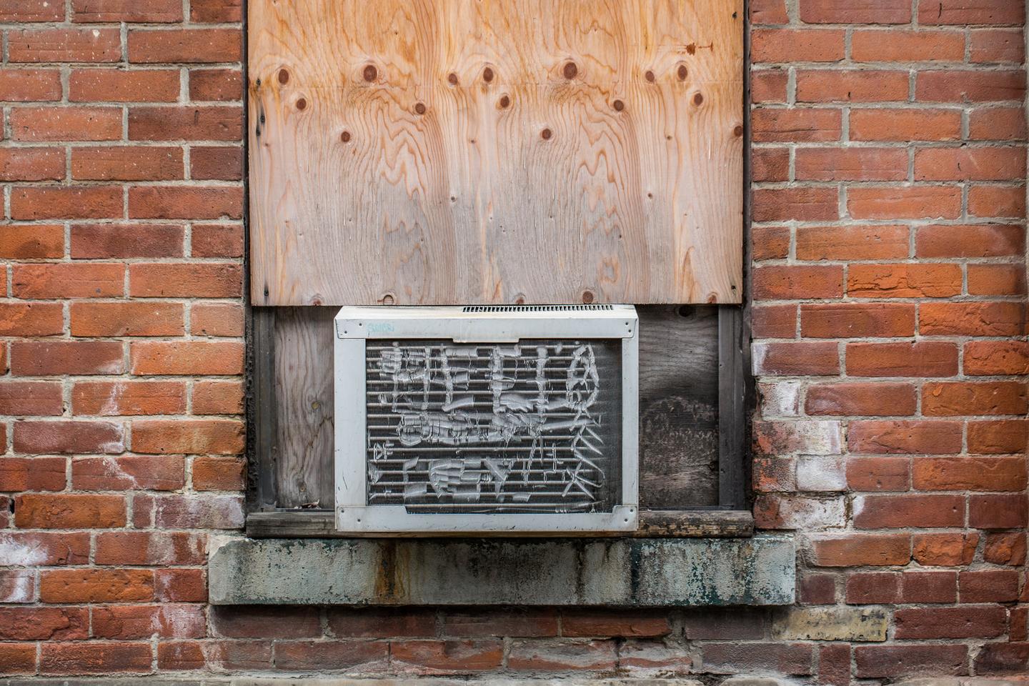 Old air conditioning unit set into a weathered brick wall